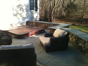 Stone deck, wall, and hot tub by Don Nyren Masonry in Wellesley, Massachusetts.